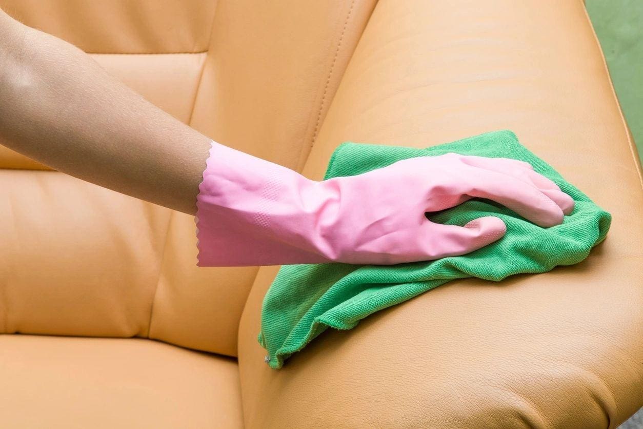 A person cleaning the arm of a couch