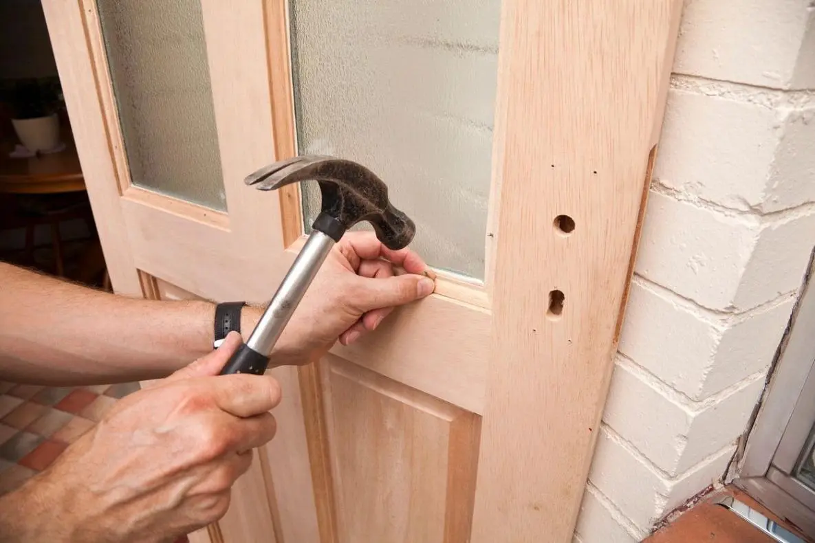 a man fixing a door with a hammer